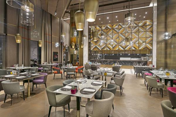 Innenansicht des Restaurants im Cullinan Belek Hotel mit gedeckten Tischen und modernen Leuchten.