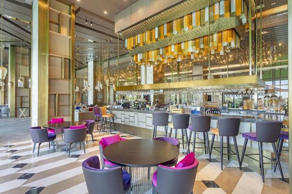 Innenbereich des Cullinan Belek Hotels mit Bar, Tischen und Stühlen.