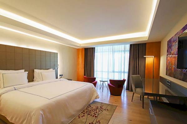 Hotelzimmer im Gloria Serenity Resort mit großem Bett, Sesseln und Schreibtisch.