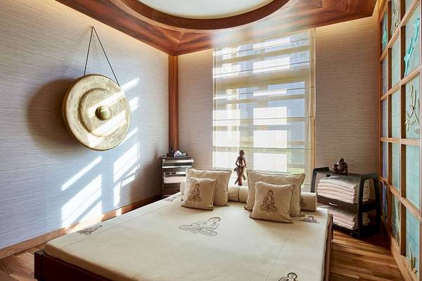 Innenansicht eines Schlafzimmers im Gloria Serenity Resort mit einem großen Bett, Kissen und einer Wand mit einem Gong.