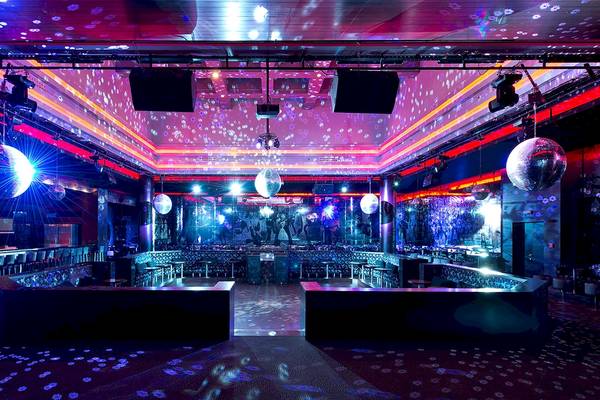 Disco-Saal im Gloria Serenity Resort mit lila und blauer Beleuchtung, Spiegelkugeln und Bar.