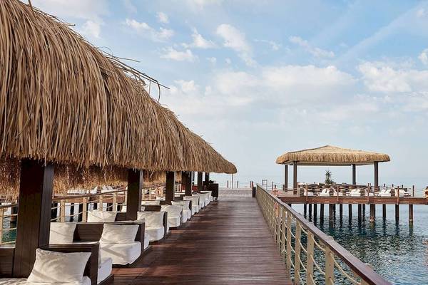 Außenbereich des Gloria Serenity Resorts mit Pier, Strohhütten und Strand-Liegestühlen