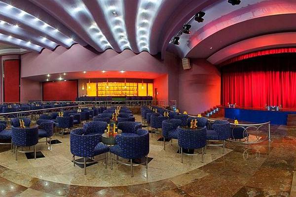 Lobby-Lounge des Iberostar Selection Rose Hall Suites Hotels mit blauen Stühlen und roter Bühne.