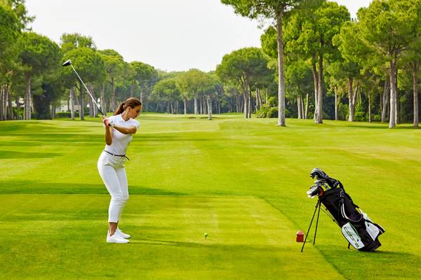 Eine Frau schwingt einen Golfschläger auf einem Golfplatz.
