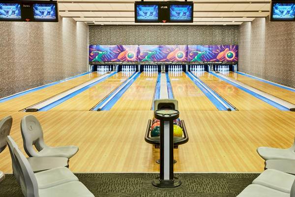 Bowlinghalle des Gloria Serenity Resort mit Bowlingbahnen, Monitoren und leeren Sitzen.