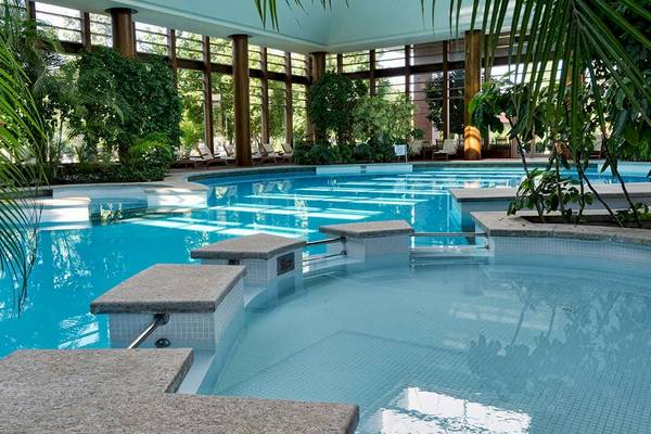 Pool im Gloria Serenity Resort mit Glaswänden und Palmen.