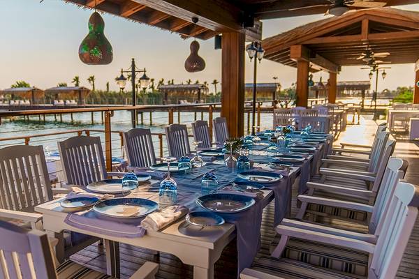 Terrasse im Gloria Serenity Resort mit Blick auf das Wasser und gedecktem Tisch.