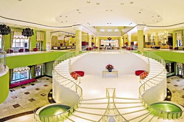 Innenbereich des Iberostar Selection Rose Hall Suites Hotels mit einer spiralförmigen Treppe und Blumen.