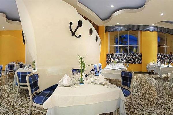 Innenansicht des Restaurants im Iberostar Selection Rose Hall Suites Hotel mit blauen Stühlen und weißen Tischdecken.