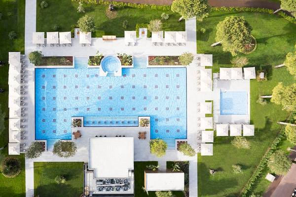 Luftaufnahme des Schwimmbads im Gloria Serenity Resort mit Liegestühlen und grüner Umgebung.