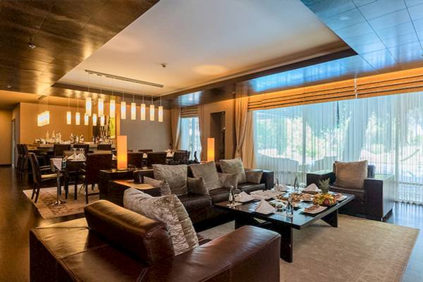 Innenbereich des Gloria Serenity Resorts mit Sofas, Tischen und einer Bar im Hintergrund.