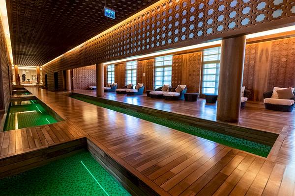 Innenbereich des Gloria Serenity Resorts mit Holzboden und grünen Wasserbecken