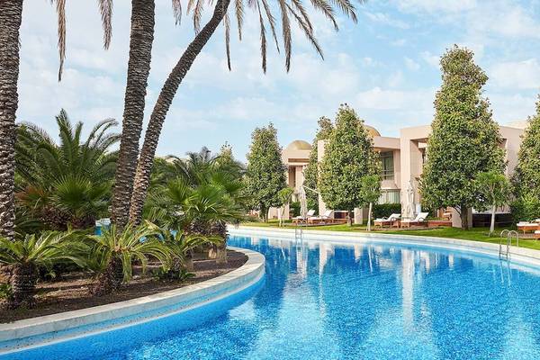 Außenpool des Gloria Serenity Resort mit Loungeliegen und tropischen Bäumen.