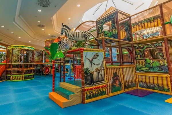 Indoor Spielplatz im Gloria Serenity Resort mit bunten Spielgeräten, Tierfiguren und blauem Boden.