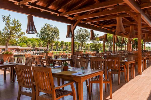Außenrestaurant des Gloria Serenity Resorts mit Holztischen und Stühlen.