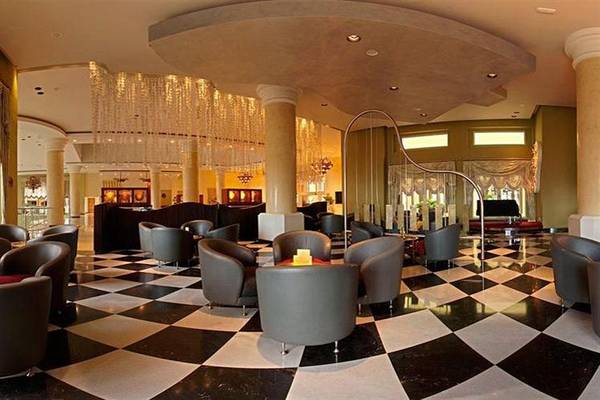 Lobby des Iberostar Selection Rose Hall Suites Hotels mit schwarzen und weißen Fliesenboden und mehreren Sitzgelegenheiten.