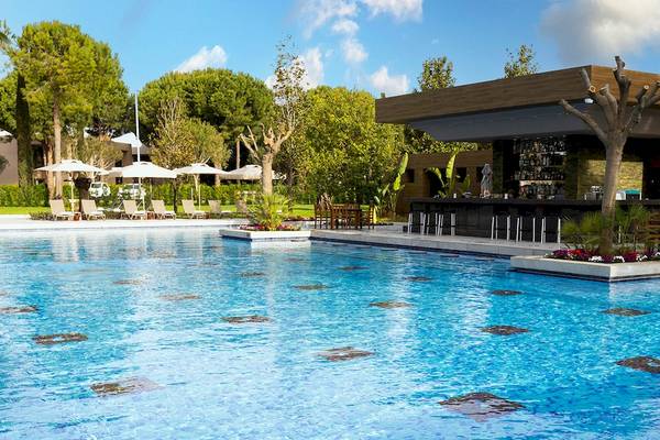 Pool mit Bar im Gloria Serenity Resort mit Loungestühlen und Sonnenschirmen