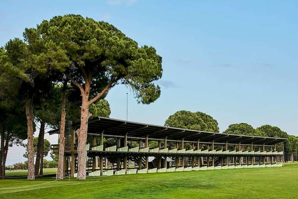 Außenansicht des Golfplatzes vom Gloria Golf Resort mit grünen Rasen und hohen Bäumen.
