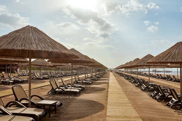 Strand des Gloria Golf Resorts mit vielen Liegestühlen und Sonnenschirmen.