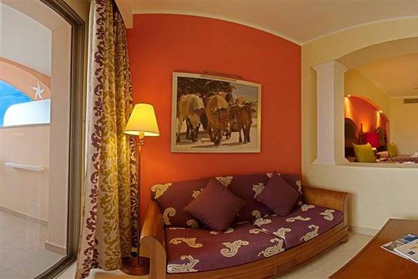 Wohnbereich im Iberostar Selection Rose Hall Suites Hotel mit einem Sofa, einem Tisch und einem Bild an der Wand.