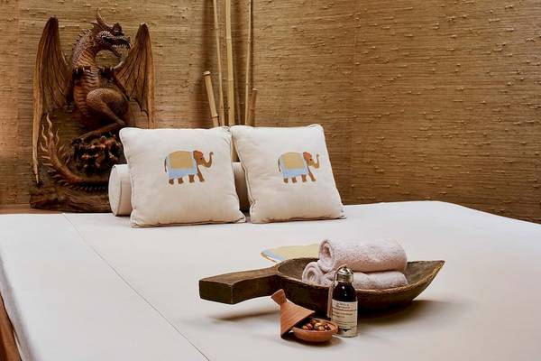 Bett im Gloria Golf Resort Spa mit weißen Laken, zwei Kissen mit Elefantenmuster und einem Holztablett mit Gegenständen.