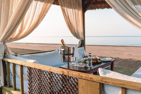Strandsitzbereich des Gloria Golf Resort mit einer Flasche Champagner und Früchten.