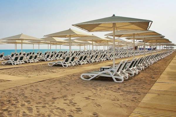 Strand des Gloria Golf Resorts mit vielen Liegestühlen und Sonnenschirmen