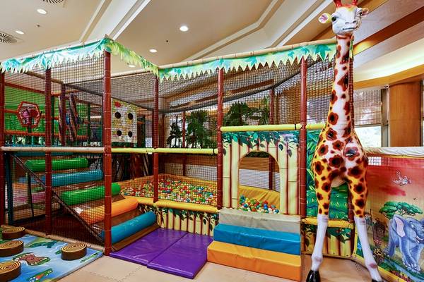 Kinderspielplatz im Gloria Golf Resort mit bunten Spielgeräten und einer großen Giraffenfigur.