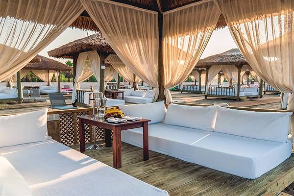 Strandlounge im Gloria Golf Resort mit weißen Liegen und Vorhängen.