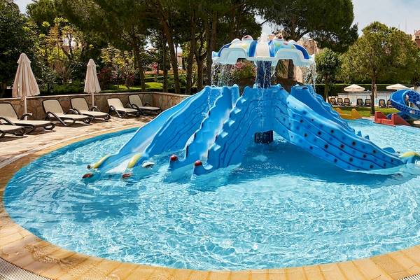 Wasserrutsche im Gloria Golf Resort mit blauem Wasser und umliegenden Sonnenliegen.