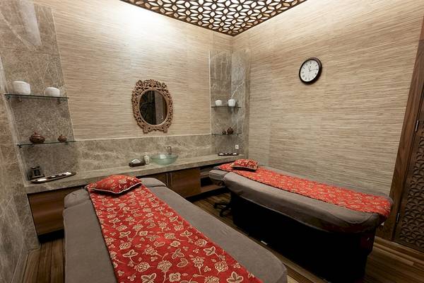 Massageraum im Gloria Golf Resort mit zwei Betten, Tisch, Spiegel und Uhr.