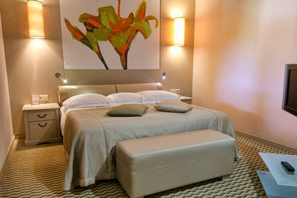 Schlafzimmer im Gloria Golf Resort Hotel mit großem Bett, Nachttischen und Fernseher.