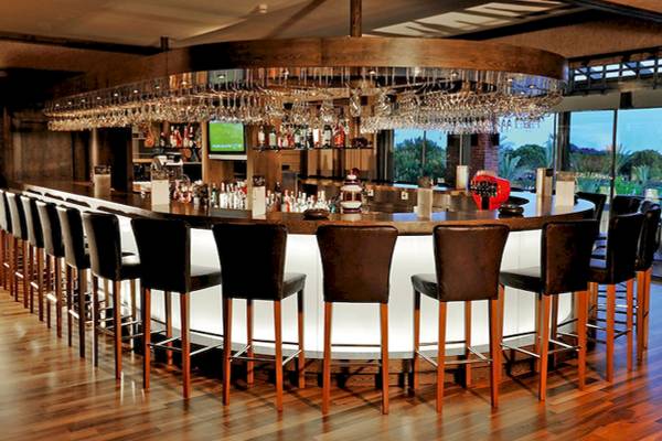 Barbereich im Gloria Golf Resort mit runden Lederstühlen und einer Glasflaschen-Bar.