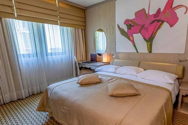 Schlafzimmer im Gloria Golf Resort mit einem großen Bett, Beistelltischen und einem Wandgemälde.
