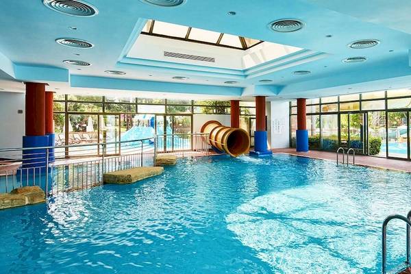 Indoor-Pool des Gloria Golf Resort mit Rutsche und blauen Säulen