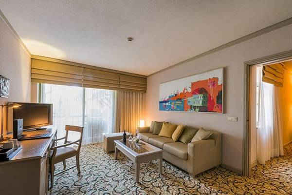 Wohnbereich der Suite im Gloria Golf Resort mit Couch, Schreibtisch und Fernseher.