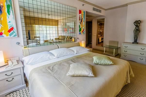 Schlafzimmer im Gloria Golf Resort Hotel mit einem großen Bett, zwei Kissen, einem Nachttisch und einem Spiegel