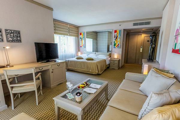 Suite-Zimmer im Gloria Golf Resort mit Bett, Schreibtisch, Fernseher und Couch.