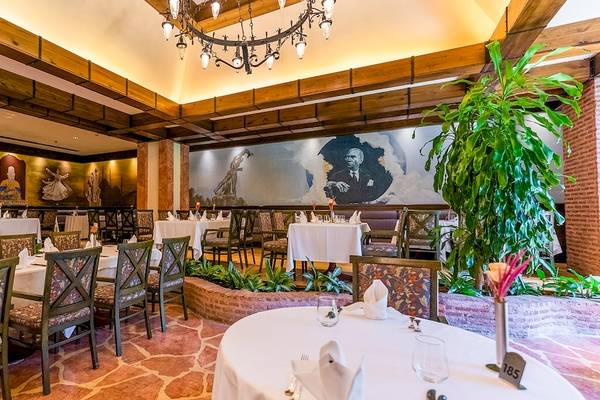 Innenansicht des Restaurants im Gloria Golf Resort mit Tischen, Stühlen und Kunstwerken an den Wänden.