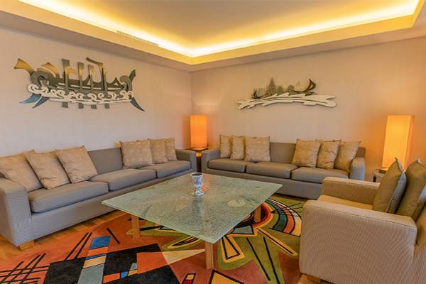 Wohnbereich im Gloria Golf Resort mit zwei Sofas, einem Glastisch und dekorativen Wandelementen.