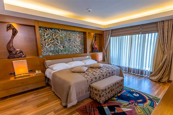 Schlafzimmer im Gloria Golf Resort mit einem großen Bett, Dekor und Teppich vor dem Fenster.