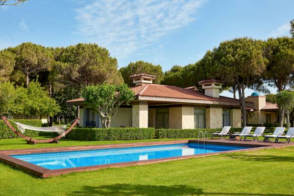 Außenansicht des Gloria Golf Resorts mit Pool, Lounges und gepflegtem Rasen.