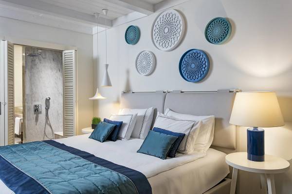 Schlafzimmer im Titanic Luxury Collection Bodrum mit weißem Bett, blauen Kissen und modernen Dekorelementen.