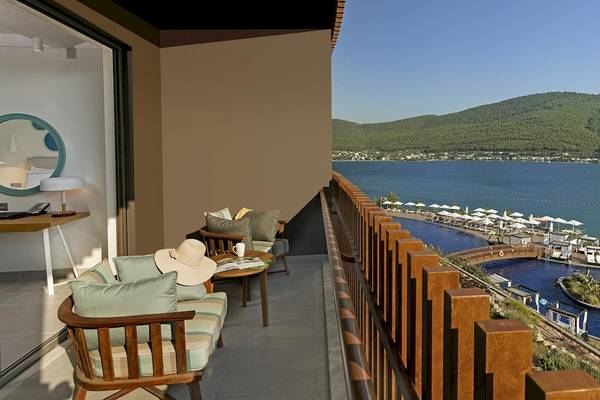 Terrasse mit Meerblick im Titanic Luxury Collection Bodrum Hotel, mit Möbeln und einem Swimmingpool im Hintergrund.