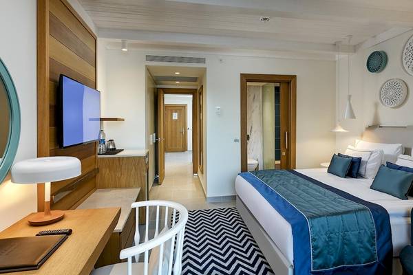Zimmer im Titanic Luxury Collection Bodrum mit großem Bett, Fernseher, Schreibtisch und Deko-Elementen.