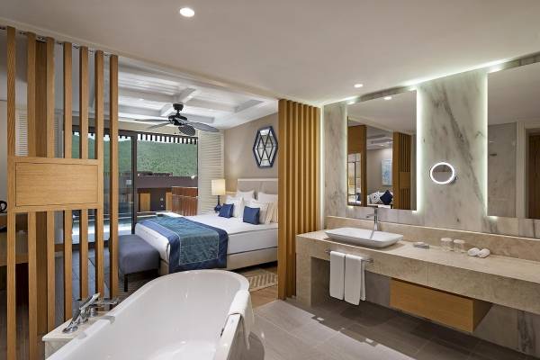 Innenansicht einer Suite im Titanic Luxury Collection Bodrum Hotel mit Badewanne und Badezimmer.