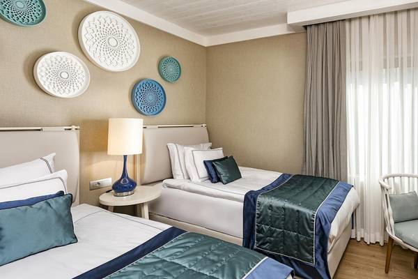 Zwei Doppelbettzimmer im Titanic Luxury Collection Bodrum mit modernen Möbeln und Dekor.
