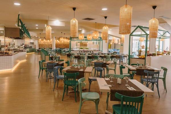 Innenansicht des Restaurants im Hotel Suites & Villas By Dunas mit vielen Tischen und Stühlen, Holzboden und Hängelampen.