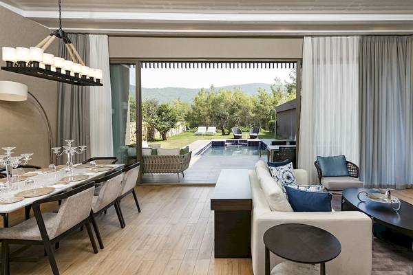 Innenansicht des Wohnbereichs des Titanic Luxury Collection Bodrum mit großem Fenster und Blick auf den Pool.