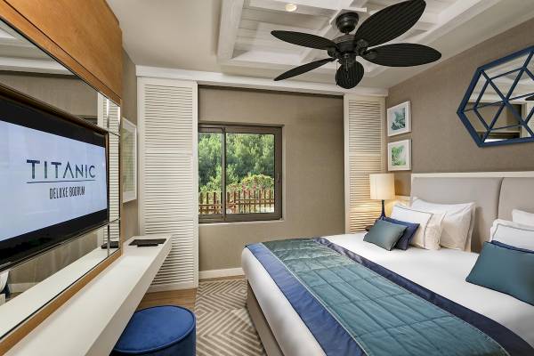 Das Zimmer des Titanic Luxury Collection Bodrum mit einem Fernseher, einem Bett und einem Fenster.